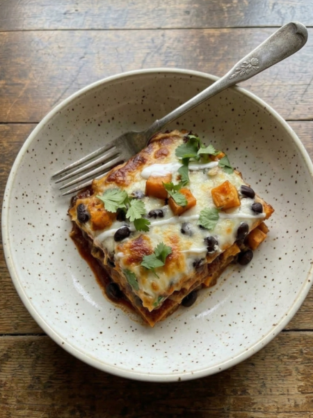 Slice of beef enchilada bake with sweet potatoes, black beans, melted cheese, and cilantro