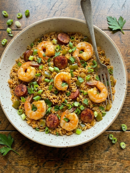 Bowl of Cajun dirty rice with shrimp, sausage, green onions, and parsley.