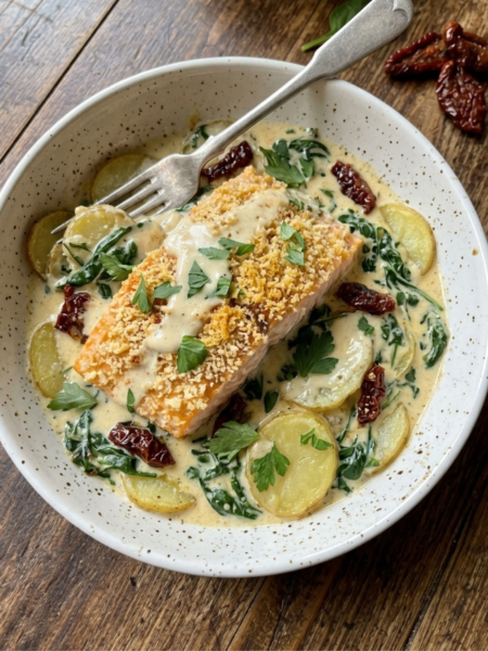 Creamy Tuscan salmon with potatoes, spinach, and sun-dried tomatoes in parmesan sauce.