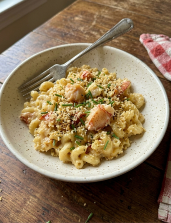 Creamy lobster mac and cheese with crispy panko and chives served in a ceramic bowl.